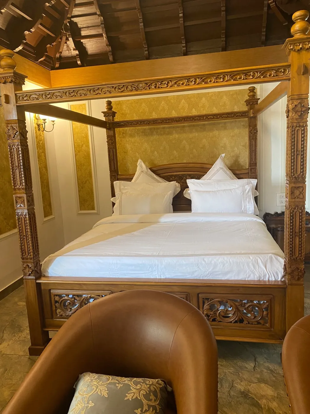 Carved wooden four-poster cot with white bed linen